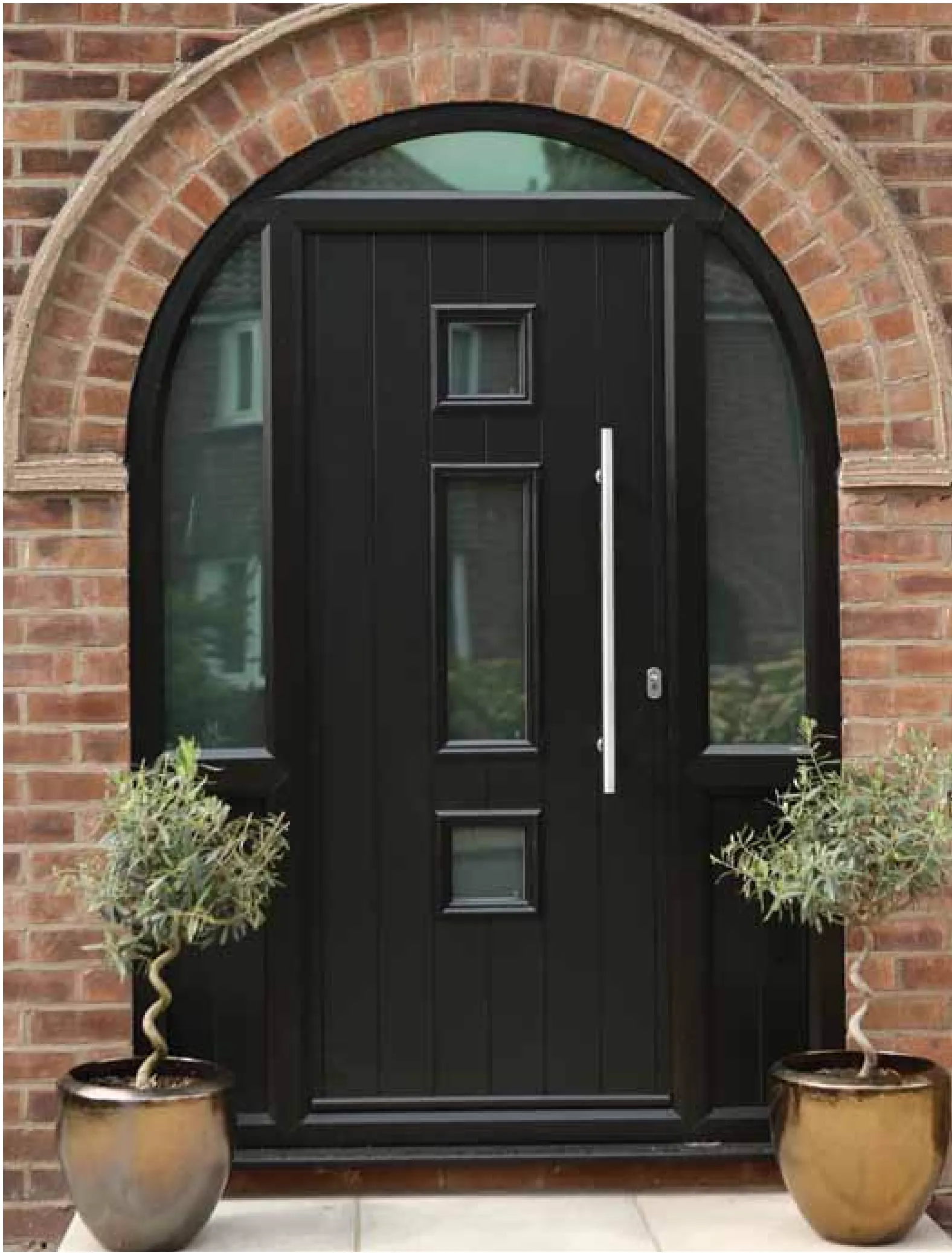 Dark entrance door beneath an arched brick surround