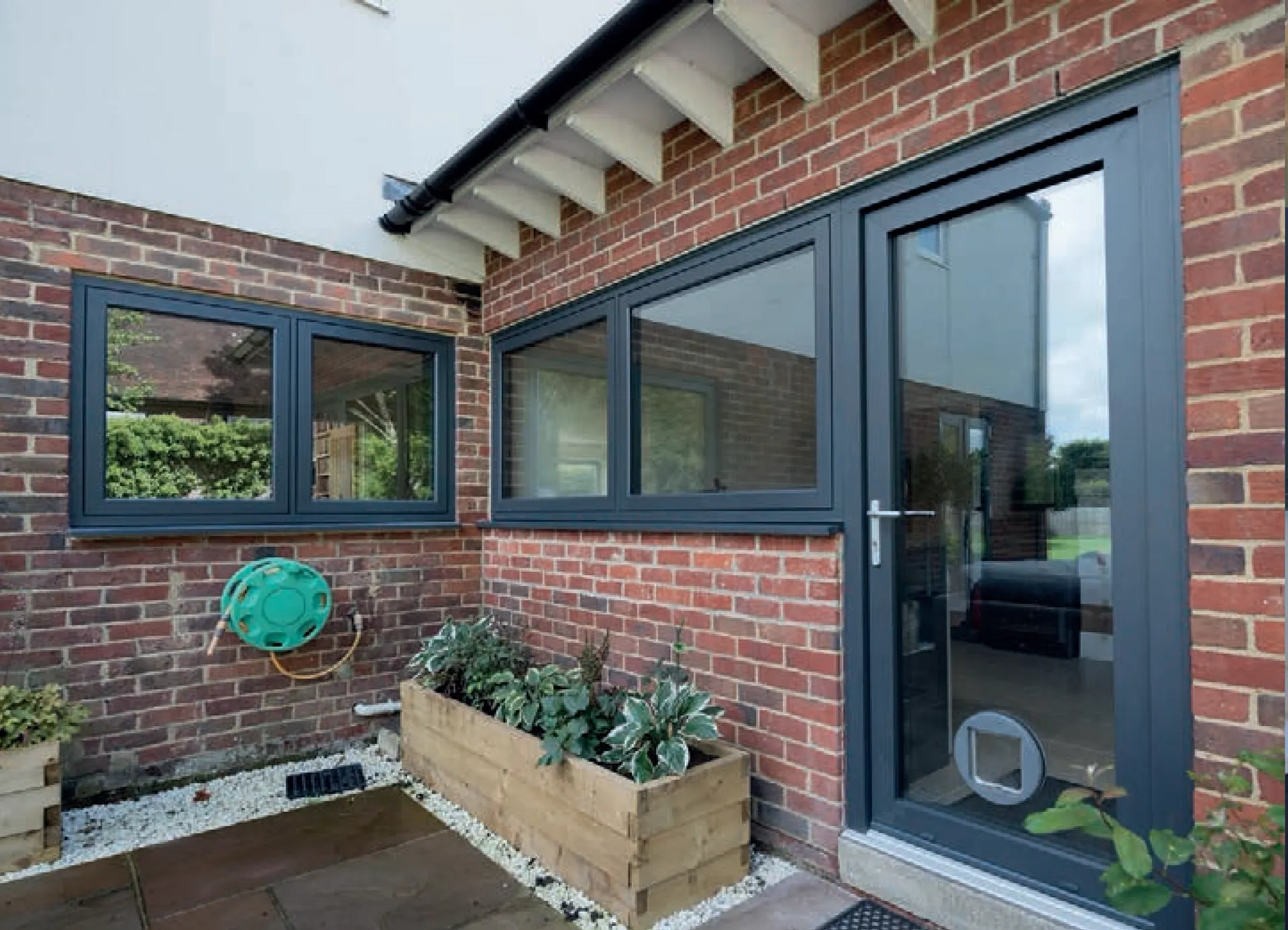 Grey French doors and windows in a brick garden-facing wall