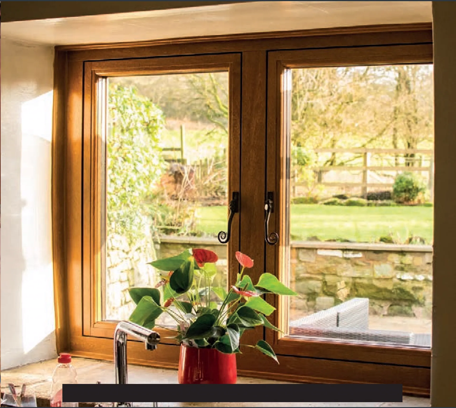 Wood-toned kitchen window looking out over a leafy garden
