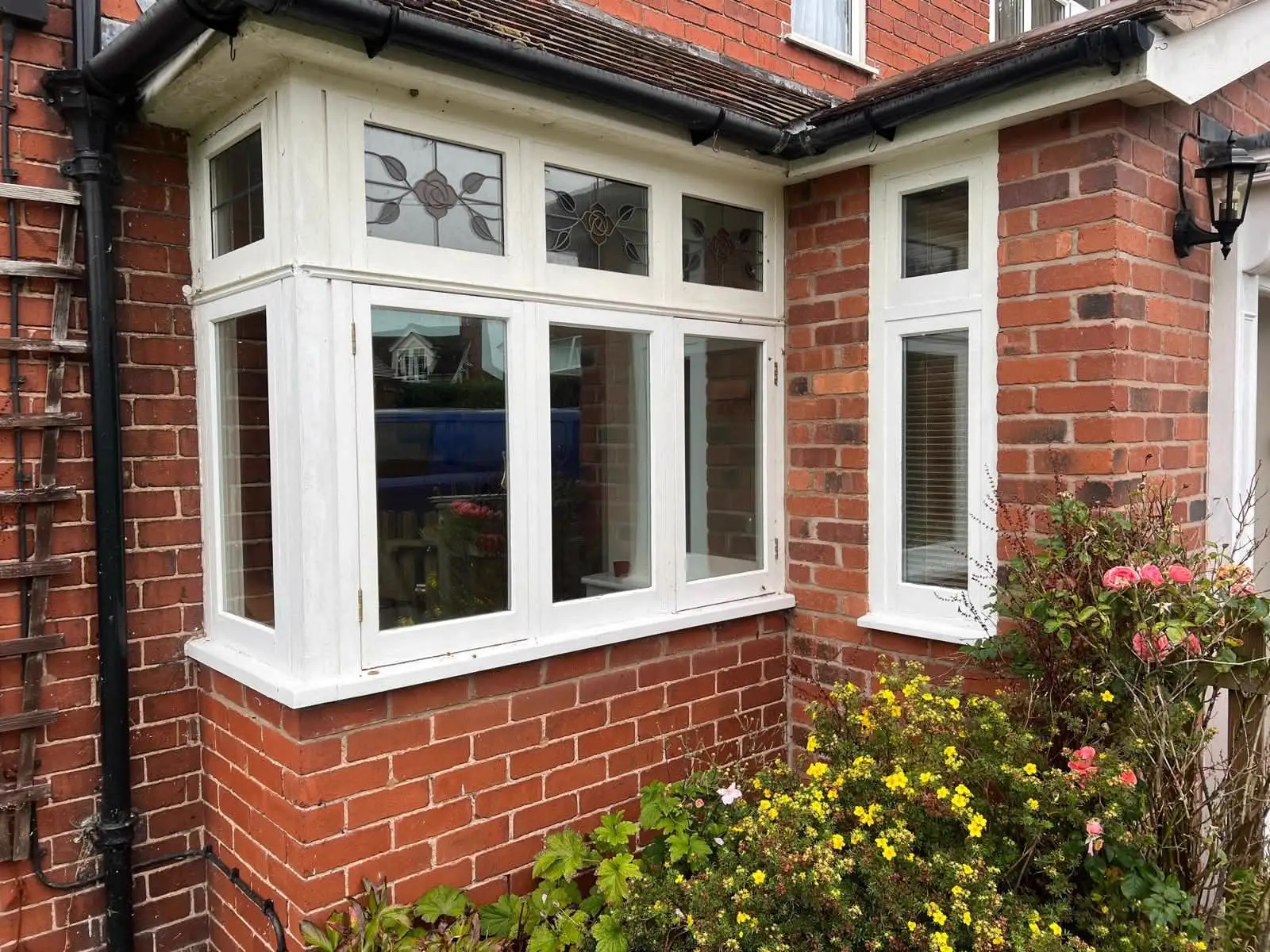 White-framed bay windows alongside a brick entrance