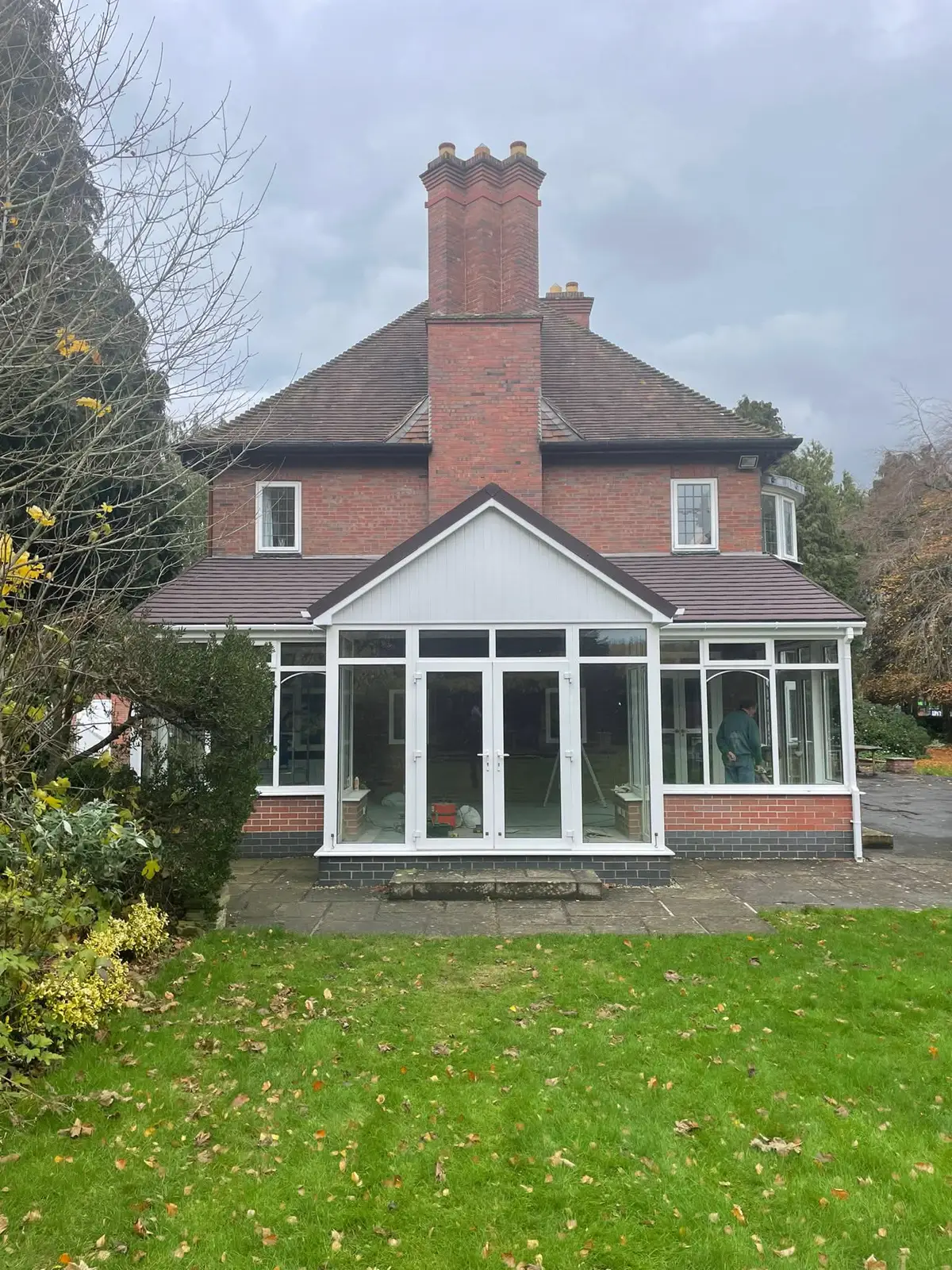 Gable-fronted conservatory beside a brick house and lawn