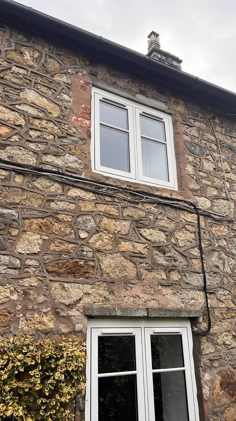 White-framed windows set into a stone house wall
