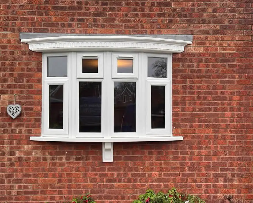 White bay window with top-opening sections in a brick façade