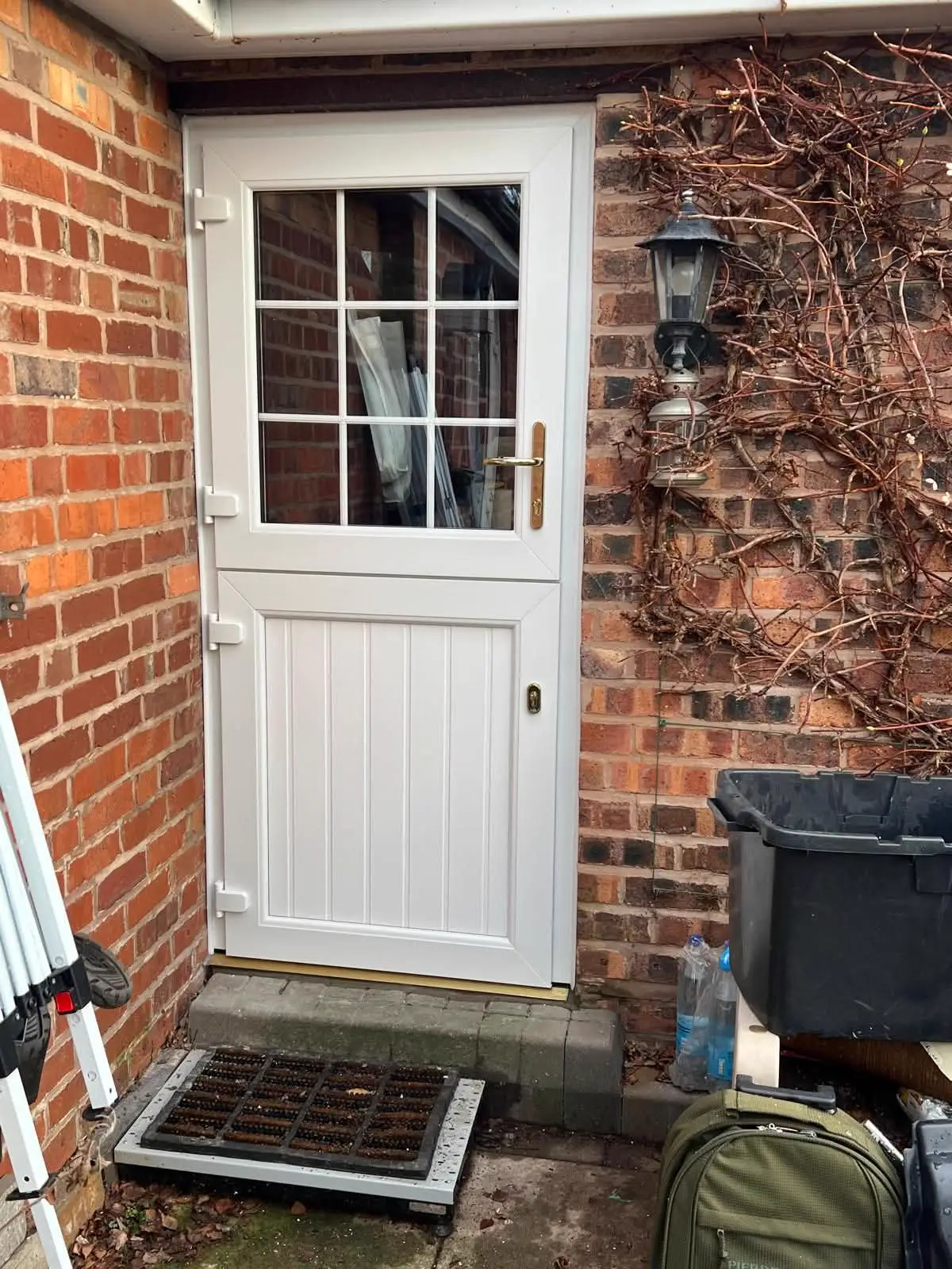 White entrance door with decorative glazing beside a brick wall